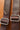 Close-up of a brown leather strap with metal buckles on a brown background