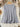 Gray long-sleeve top on a hanger with floral decorations in the background