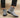 Gray suede Chelsea boots worn with black pants on a beige background
