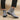 Gray suede Chelsea boots worn with black pants on a beige background