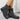 Gray suede boots with buckles worn by a person on a light gray background