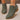 Green ankle boots with brown soles worn by a person on a neutral background