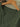 Green shirt on a wooden hanger against a tiled wall background