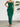Green strapless ruffled dress worn by a model against a white wall with a plant