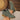 Green suede ankle boots with brown soles held by a hand on a neutral background