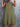 Green tiered dress worn by a person against a gray textured wall