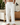 Man wearing relaxed white drawstring lounge pants in a modern living room setting
