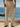 Men’s beige linen-blend drawstring pants with side buttons, styled for summer by the sea