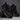 Pair of black Chelsea boots on a textured surface with a dark background