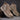 Pair of brown Chelsea boots on a textured surface with a dark background