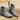 Pair of gray suede ankle boots on a wooden surface with a beige background