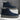 Pair of navy blue suede boots with gray soles on a white platform against a gray background