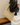 Person holding a beige woven handbag with a brown strap against a neutral background