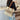 Person holding a woven handbag with a tassel in an indoor setting