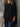 Person wearing a black oversized shirt against a stone wall