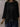 Person wearing a black oversized sweater against a textured wall