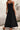 Person wearing a black slip dress against a textured wall