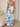 Person wearing a blue and white floral dress in a room with a beige sofa and white curtains