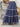 Person wearing a blue floral tiered skirt holding a straw hat on stone steps
