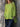Person wearing a bright green top and dark pants against a stone wall