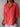 Person wearing a coral linen shirt against a wooden background