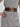 Person wearing a gray outfit with a brown belt and gold buckle on a plain background