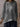 Person wearing a gray tie-dye shirt with a neutral background