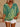 Person wearing a green and yellow patterned top with white shorts on a beige background