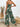 Person wearing a green leaf-patterned jumpsuit in a casual setting