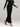 Person wearing a green long-sleeve top and black high-waisted pants on a plain background