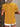 Person wearing a mustard yellow top with ruffled sleeves and white shorts against a textured wall
