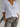 Person wearing a white button-up shirt and gray pants against a plain background