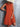 Person wearing an orange dress against a gray background