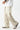 Person wearing beige wide-leg pants and striped shoes on a white background
