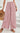 Person wearing pink floral wide-leg pants with a white background