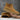 Tan Chelsea boots being held against a gray concrete background