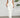 White strapless ruffled dress worn by a person against a plain background
