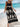 Woman in a black boho dress with white patterns standing on a beach