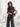 Woman in a black outfit holding a clutch in a minimalistic setting