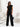 Woman in a black outfit standing in a minimalistic room