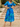 Woman in a blue floral dress standing on stone steps outdoors