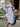 Woman in a blue off-shoulder dress holding flowers outdoors