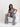 Woman in a gray jumpsuit sitting on a white chair against a white background