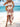 Woman in a white boho dress with red patterns standing on a beach