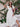 Woman in a white dress and hat standing in front of floral decorations