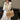Woman in a white embroidered dress carrying a cream woven hobo shoulder bag with netted center detail and brown leather strap, photographed indoors