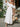 Woman in a white off-shoulder dress holding a straw bag with flowers
