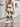 Woman wearing a beige boho dress with black patterns