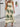 Woman wearing a beige boho dress with green patterns, motion pose