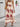 Woman wearing a beige boho dress with red patterns